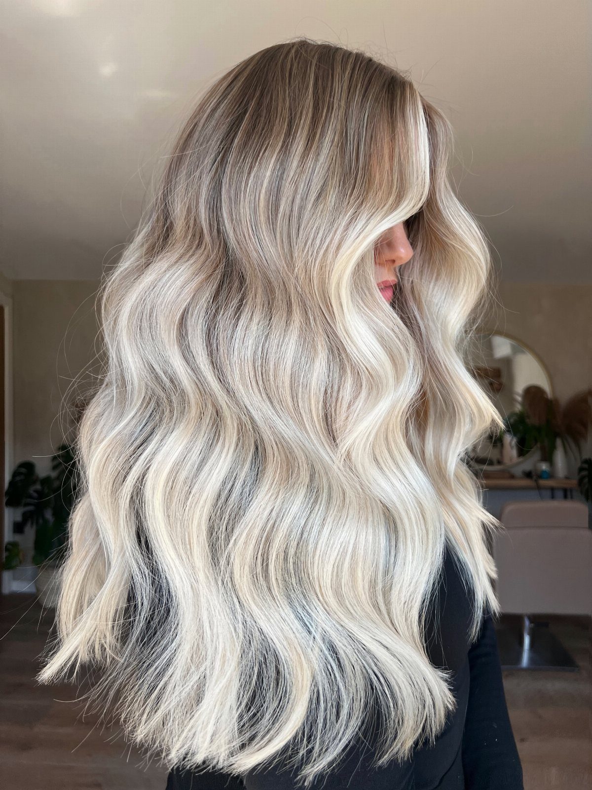Long wavy blonde balayage hair with dark roots shown from the back