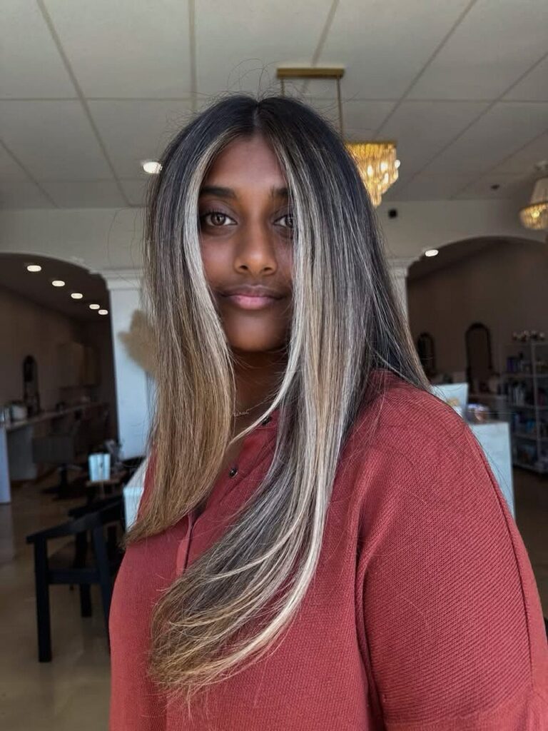 Long dark hair with bright blonde highlights framing a person’s face