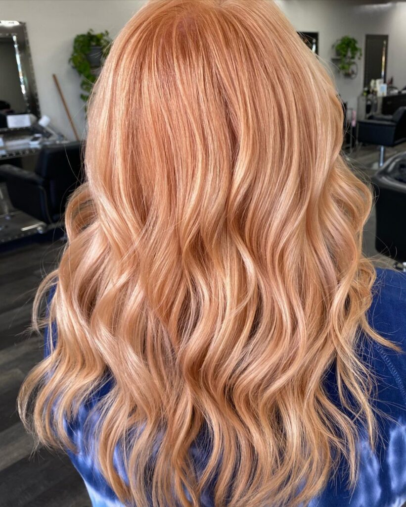 Wavy strawberry blonde hair with blonde highlights in a salon