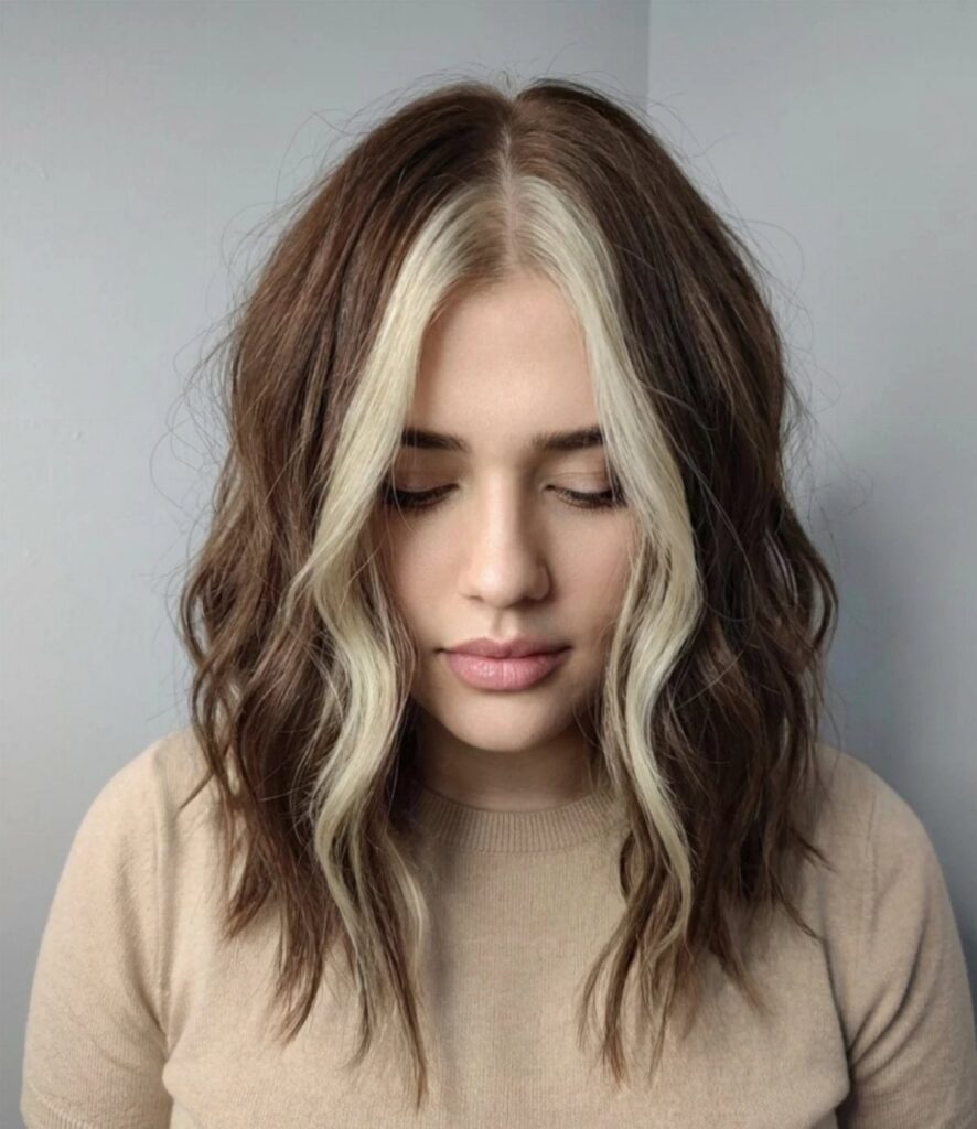 Woman with wavy brown hair and bright blonde face-framing money pieces