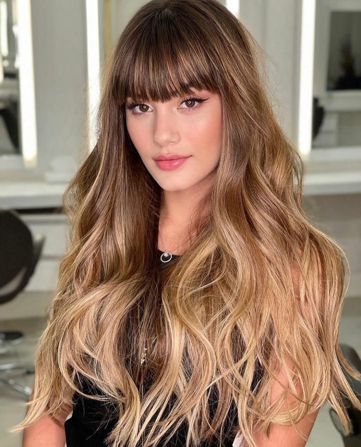 Woman showing long dark hair with creamy blonde and caramel highlights
