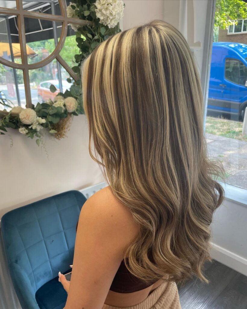 Long wavy brown hair with prominent blonde chunky highlights viewed from behind