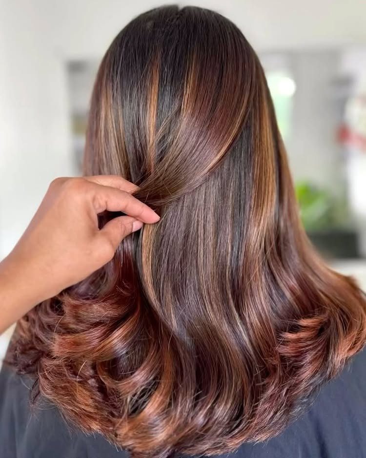 Long dark brown wavy hair with warm caramel and copper highlights