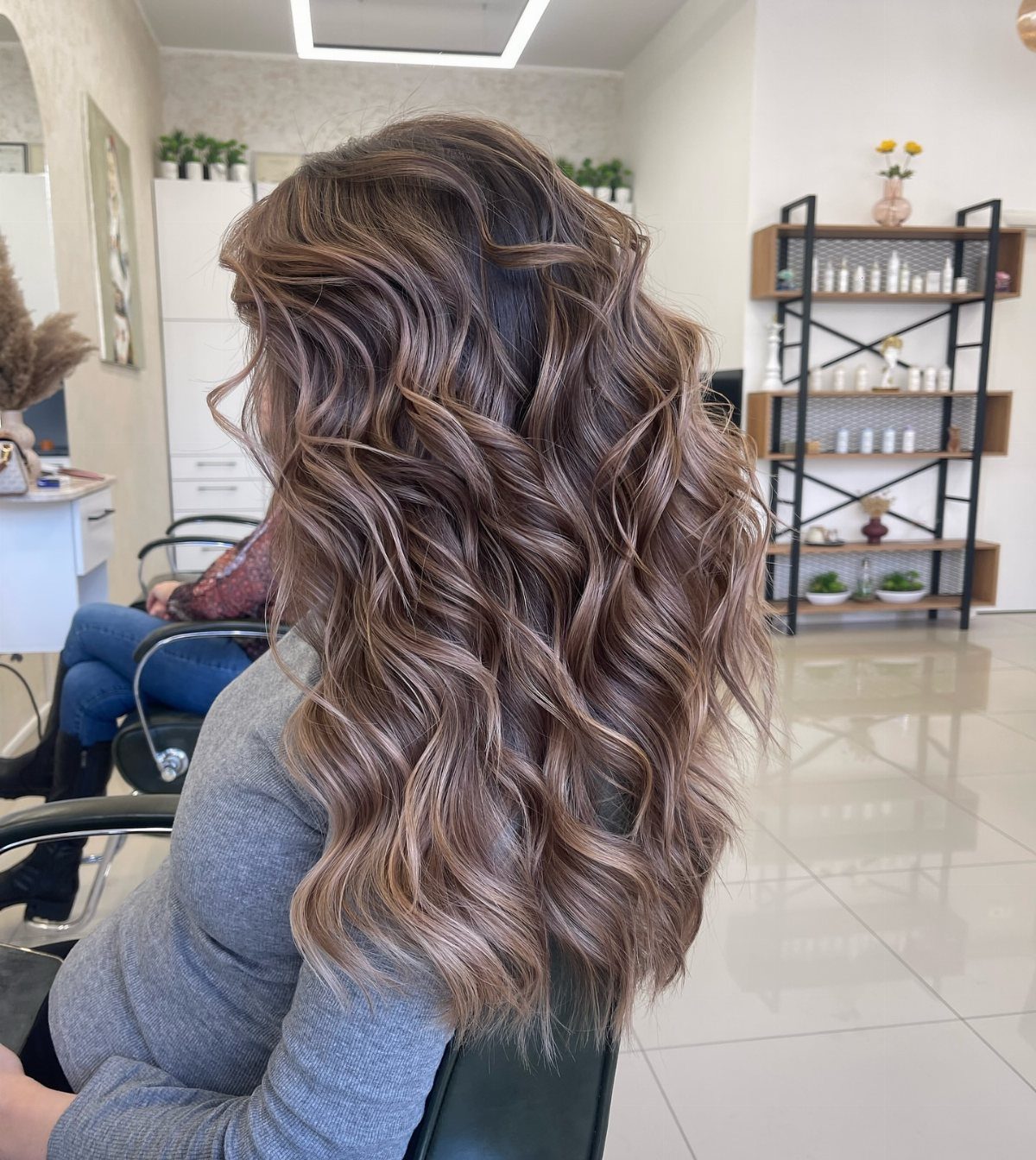 Long wavy brown balayage hair with lighter highlights styled in a bright salon
