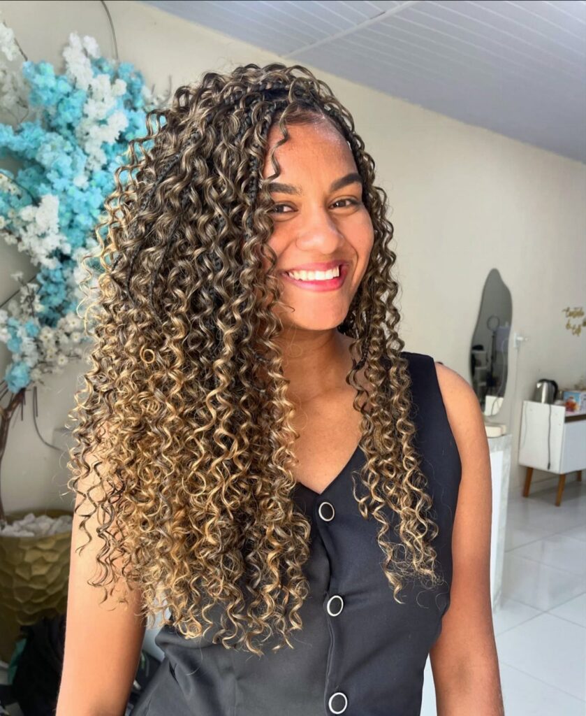 Woman with long dark curls and blonde highlights wearing a sleeveless black top