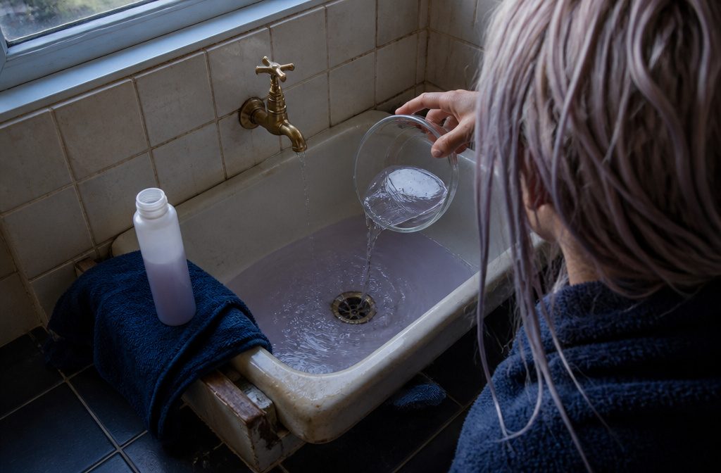 Hair with an uneven toned shade beside products used for color removal