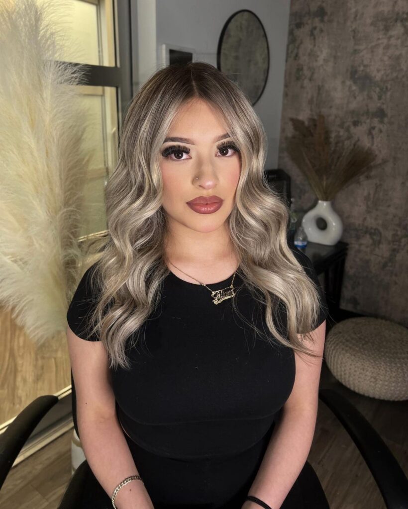 Woman showcasing wavy brown hair with light blonde highlights indoors