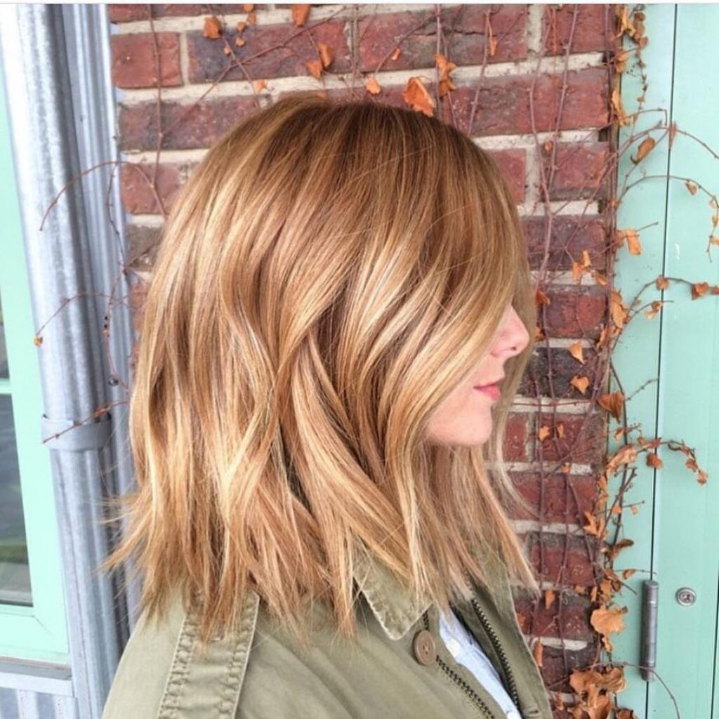 Woman showing shoulder-length reddish blonde highlighted hair in side profile