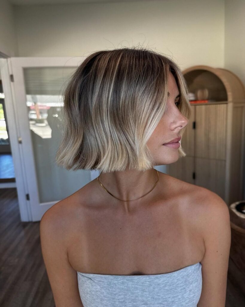 Woman showing short bob haircut with cool blonde balayage highlights